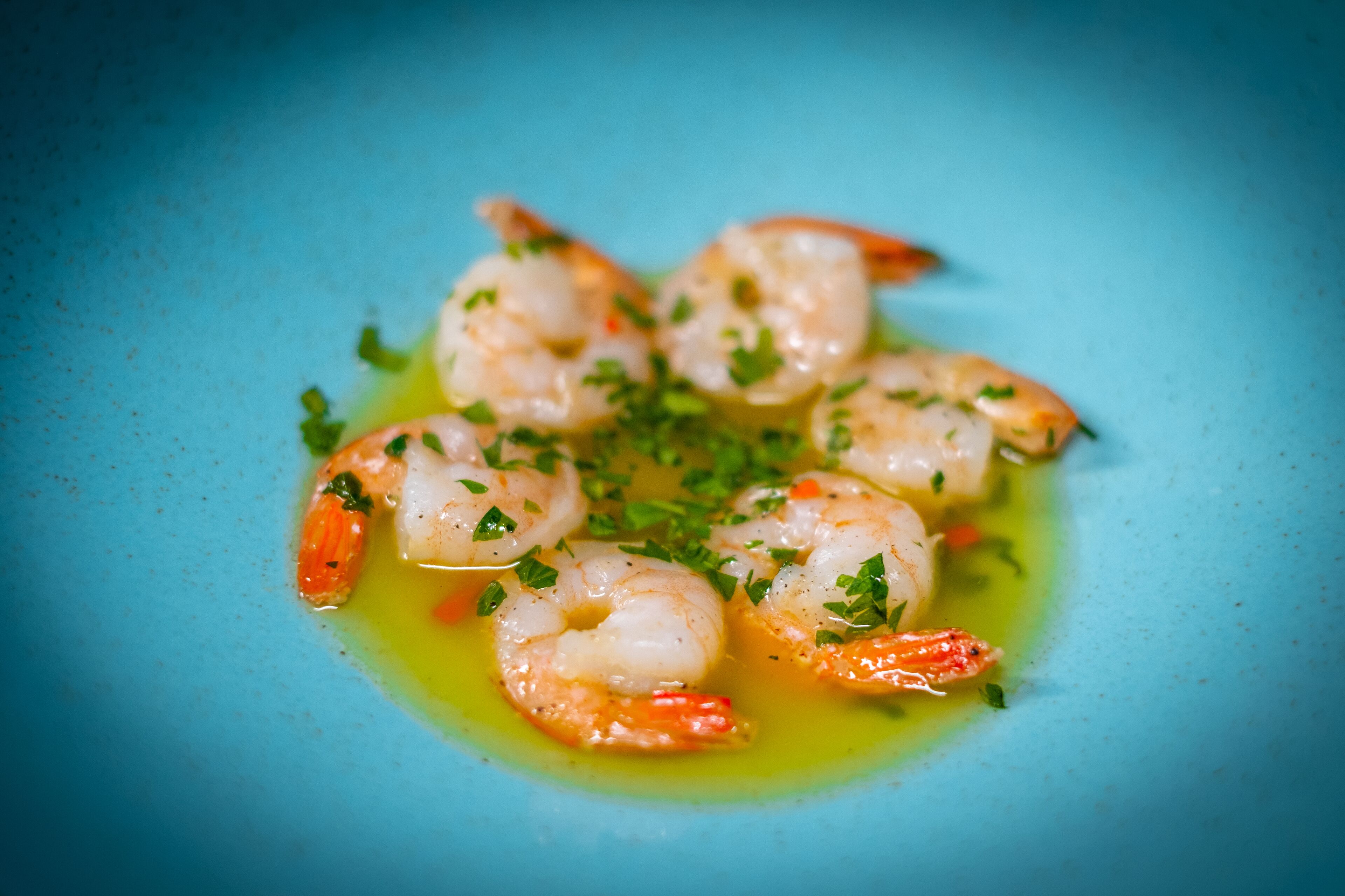 A plate of cooked shrimp garnished with herbs.