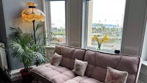 A cozy room with a cushioned bench, a potted plant, and a lamp. - The Commodore (Paignton)
