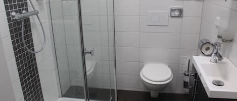 Une salle de bain moderne avec une douche à parois de verre, des toilettes blanches et un lavabo blanc avec un miroir.