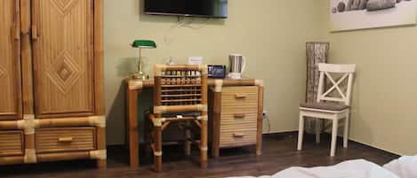 A room with a bed, a desk with a chair, a television, and a painting on the wall.