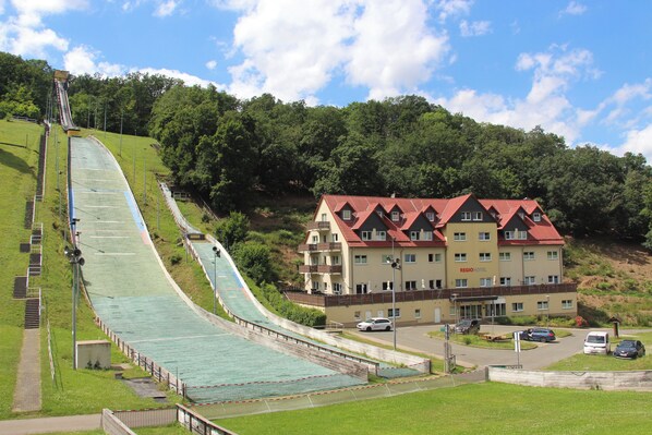 A hotel with a red-roofed building, a ski lift, and a green slope.