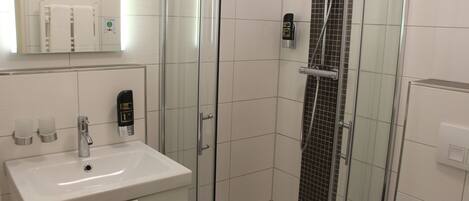 A modern bathroom with a glass-enclosed shower, a white sink, and a mirror above the sink.