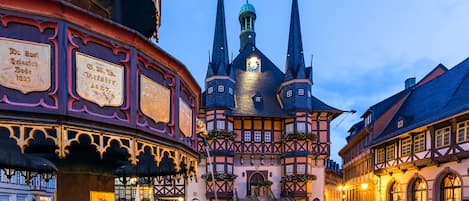 A historic building with multiple spires and a clock tower, surrounded by cobblestone streets and traditional architecture.
