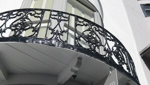 Un coin d’un bâtiment doté d’un balcon orné de balustrades en métal noir ouvragé et d’une enseigne indiquant « Aquarium Guest House ».