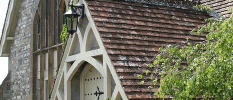 Un bâtiment en pierre doté d’une fenêtre en arc brisé, d’une porte avec une poignée noire et d’une lanterne traditionnelle.