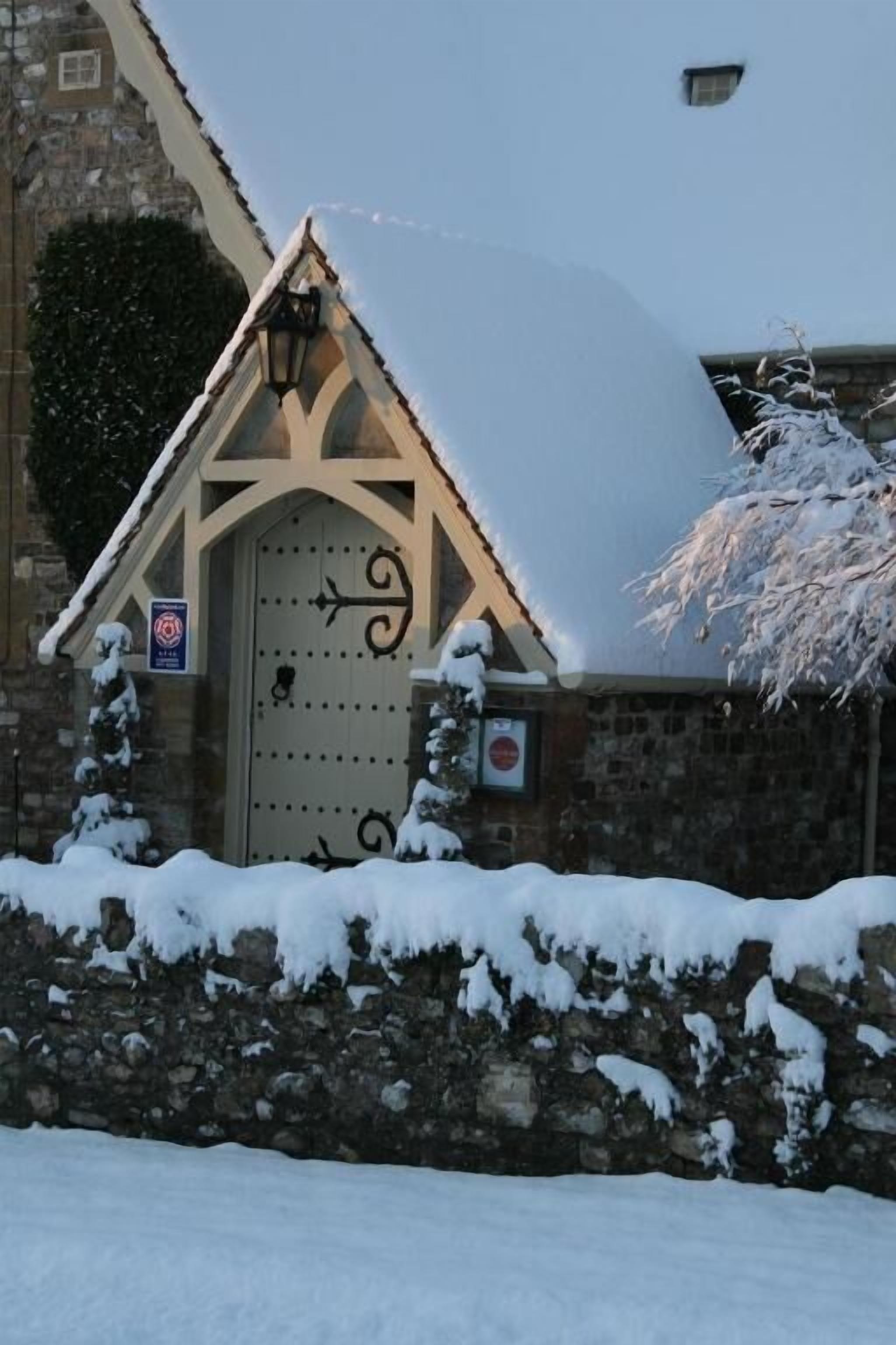 A stone building with a snow-covered roof and a decorative door.