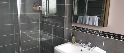 Un baño moderno con un espejo grande, un lavabo blanco y una zona de ducha.