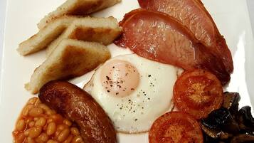 A plate of breakfast food including sausages, eggs, tomatoes, mushrooms, beans, and toast.