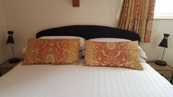 A bed with two decorative pillows, a dark headboard, and two bedside lamps on wooden nightstands.