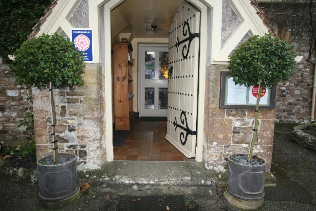 A stone archway leading to a room with a tiled floor and a door with a decorative metal gate.