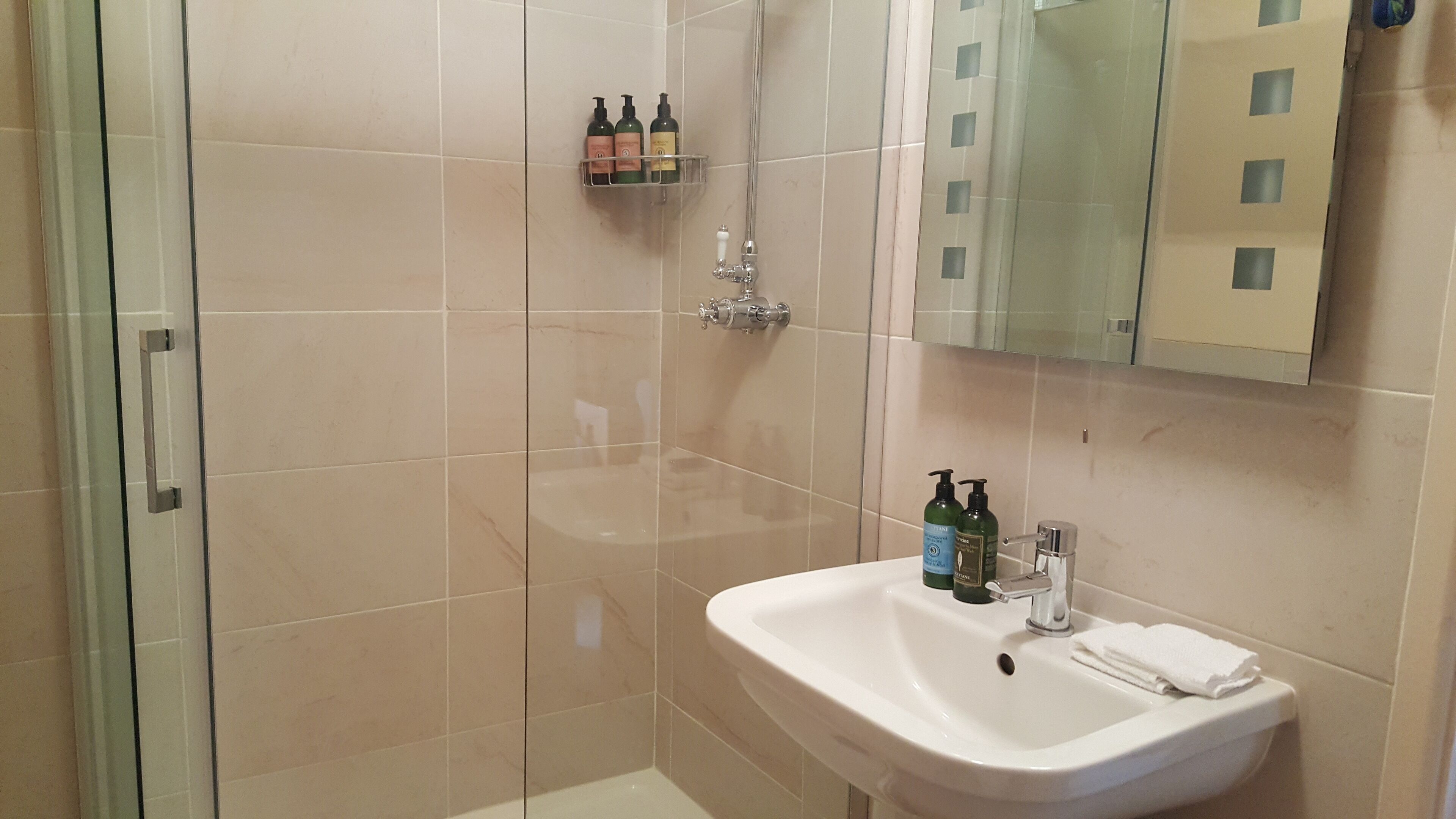 Un baño moderno con cabina de ducha de vidrio, un lavabo blanco y un espejo encima.
