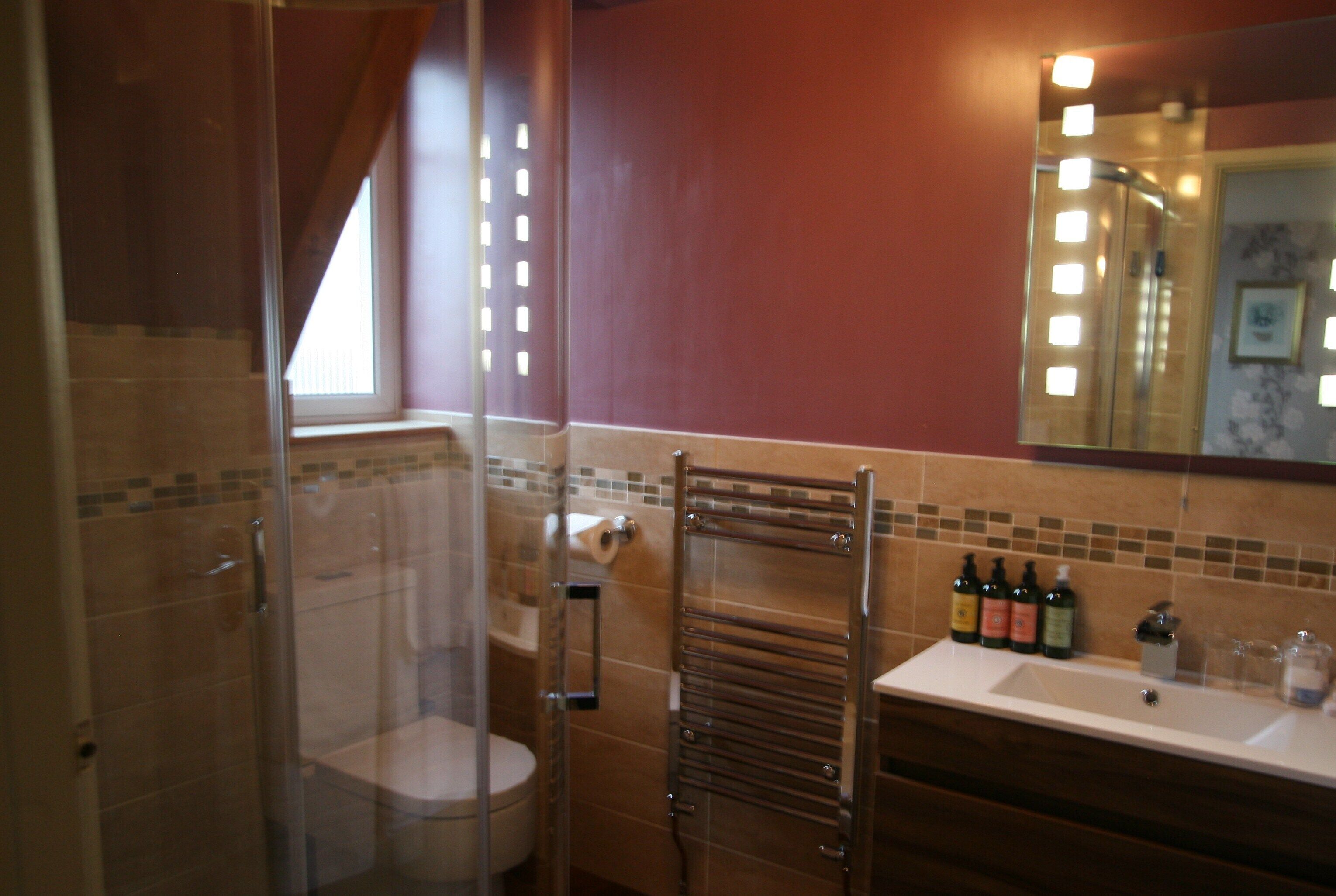 A bathroom with a glass shower enclosure, a toilet, a towel rack, and a sink with toiletries.