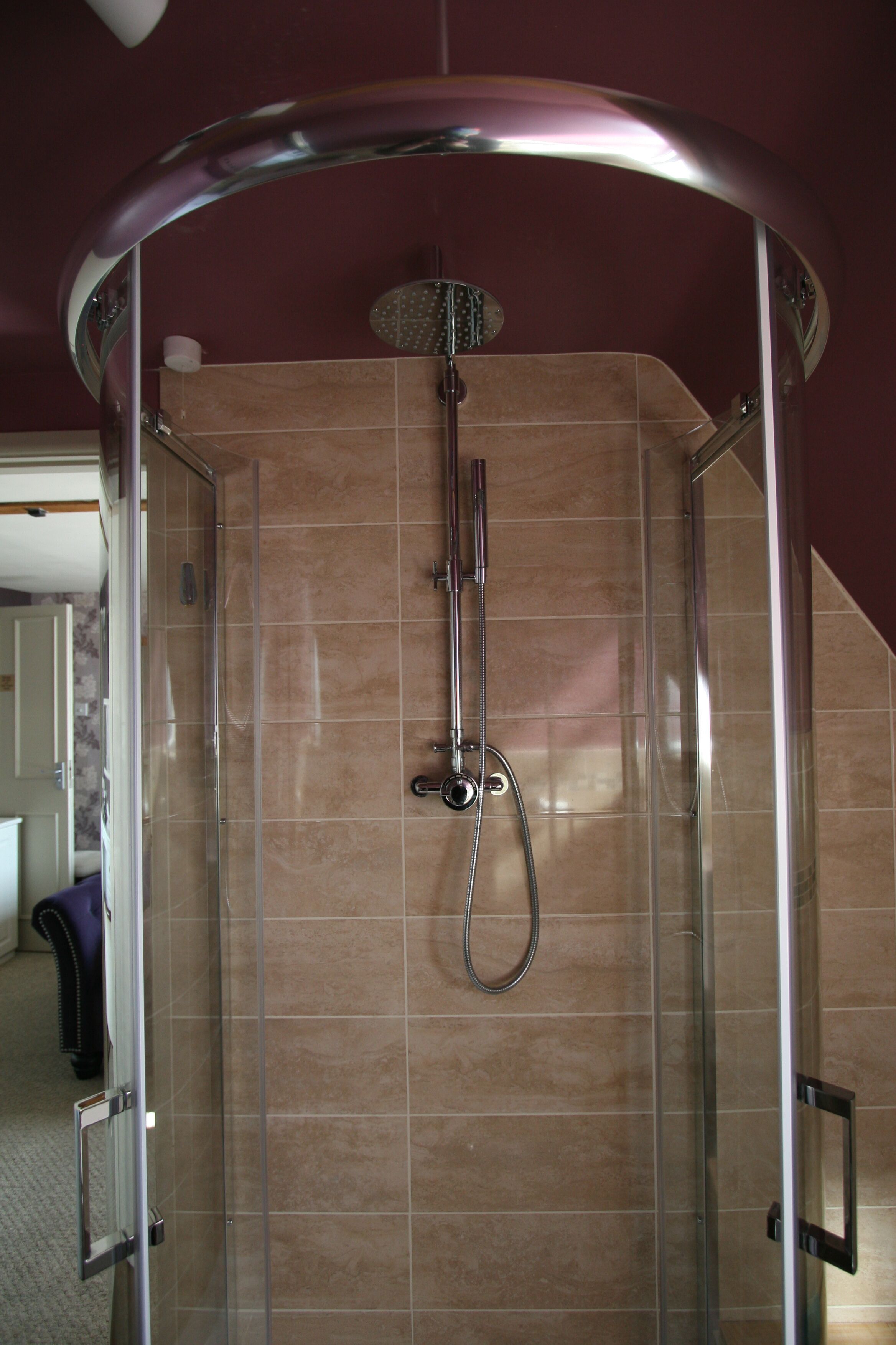 A glass-enclosed shower stall with a curved showerhead and a handheld shower attachment.