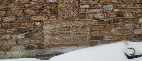 Een stenen muur met een plaquette waarop staat: 'Deze steen is gelegd door Lovett Drake, 1882'.