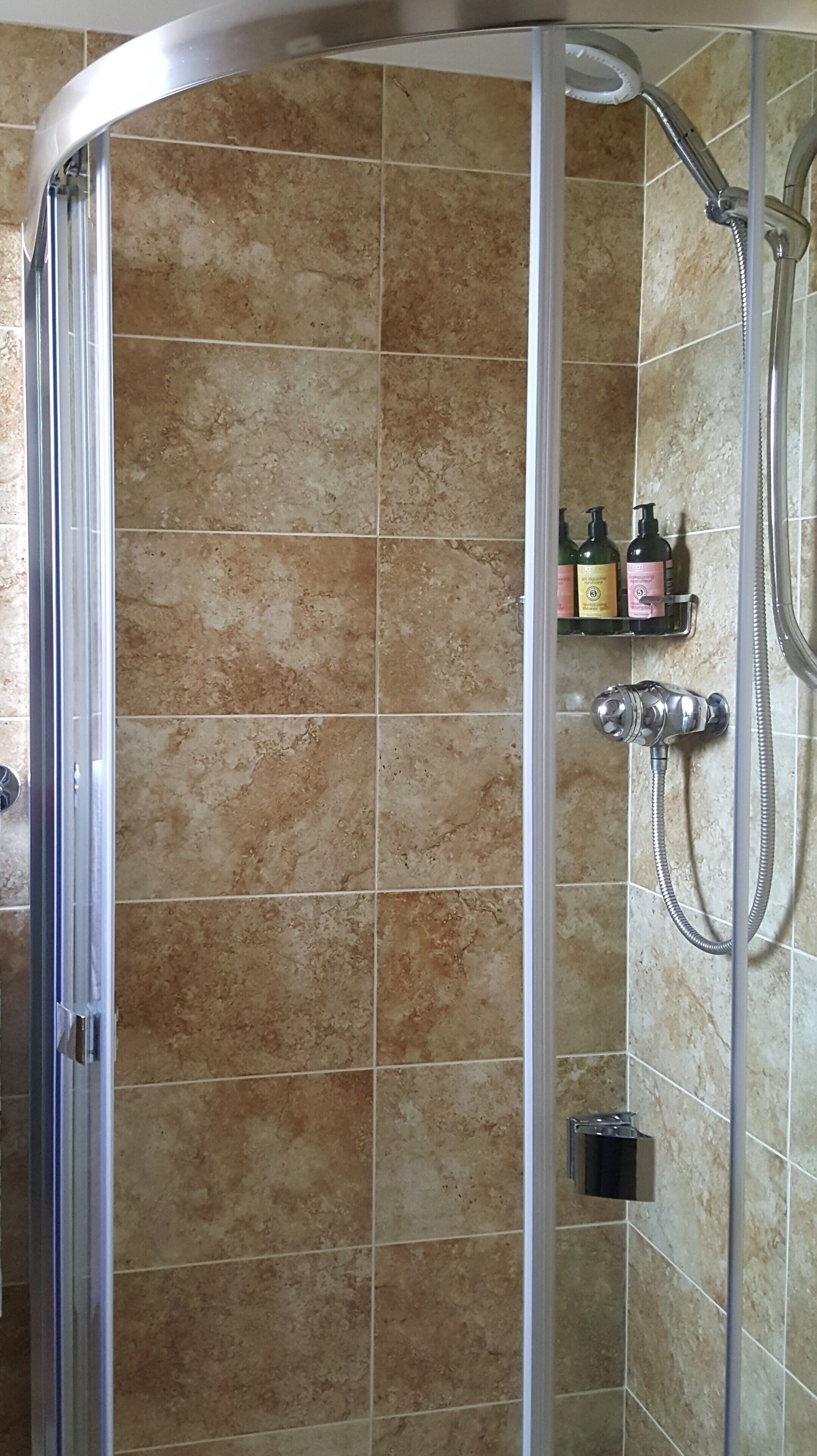 A shower area with a glass door, tiled walls, and a handheld showerhead.