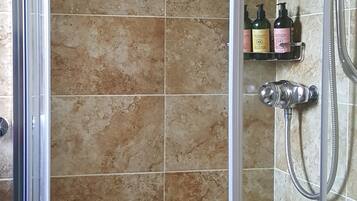 A shower area with a glass door, tiled walls, and a handheld showerhead.