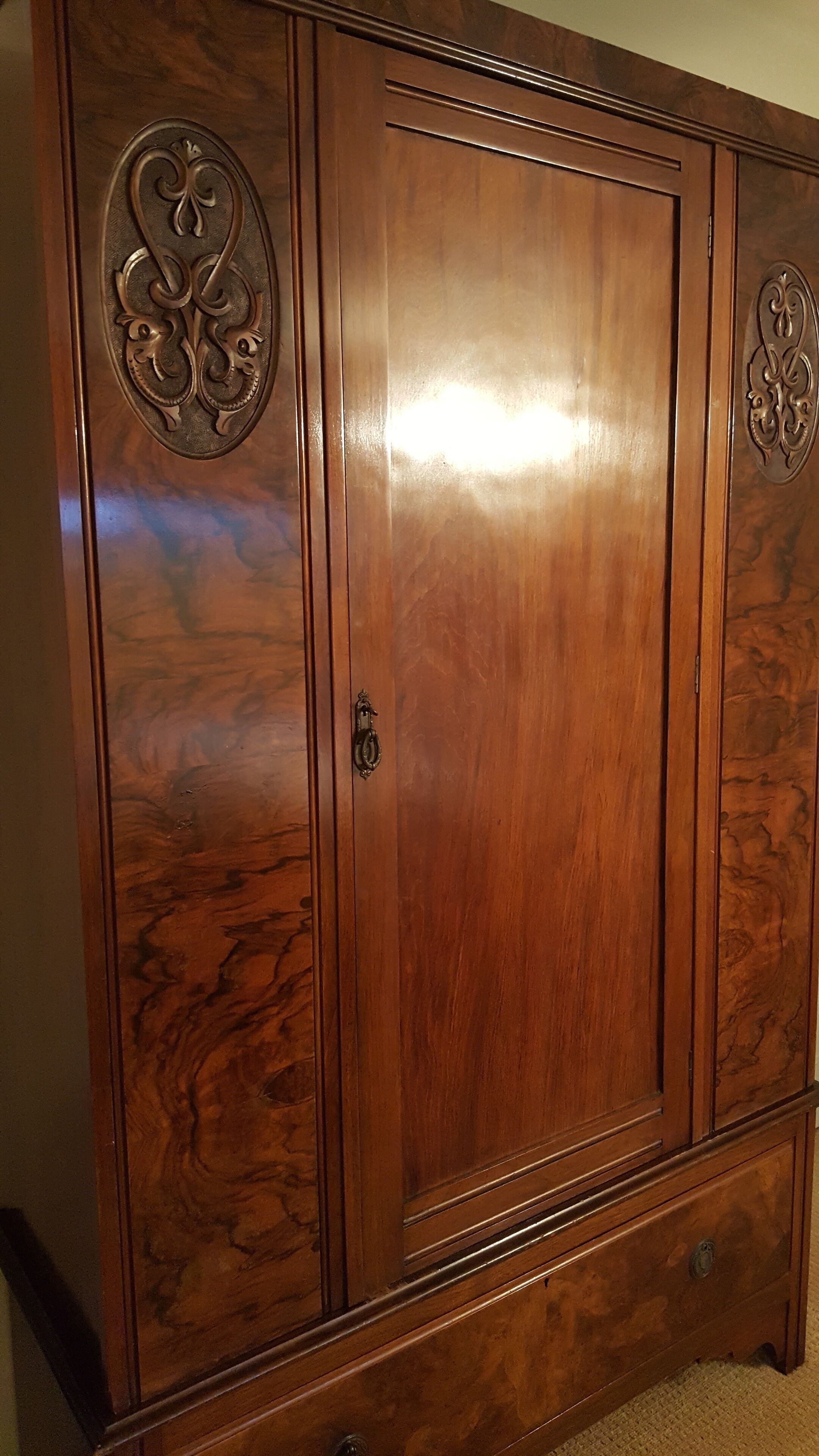 A large wooden wardrobe with ornate carvings on the doors and handles.
