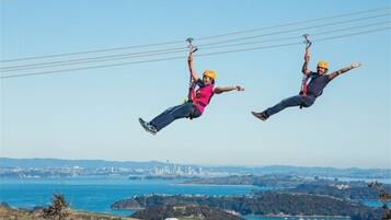 Dos personas hacen bungee jumping con un paisaje costero de fondo.