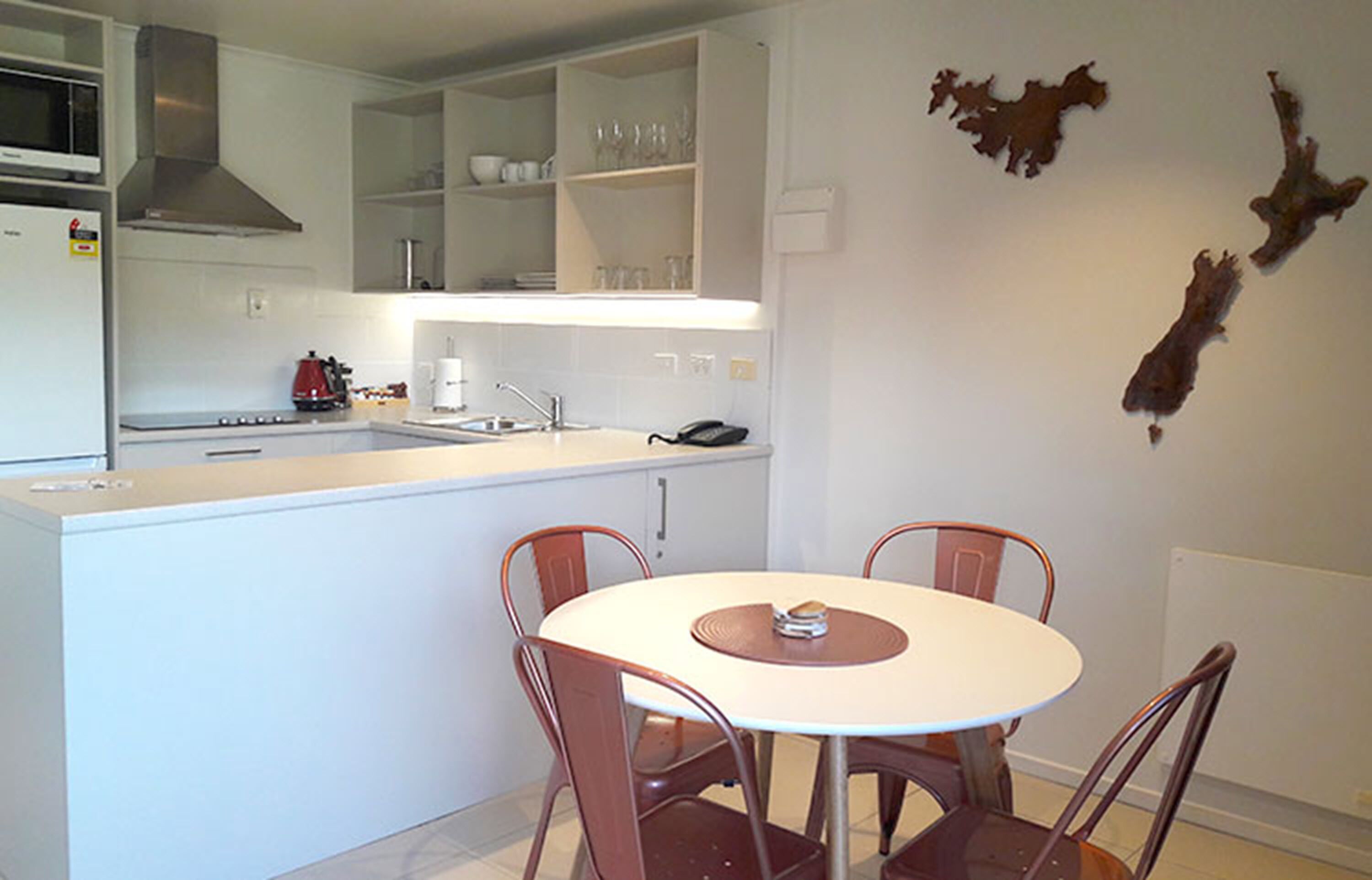 Una cocina moderna con armarios blancos, horno integrado y un comedor con una mesa redonda y cuatro sillas.