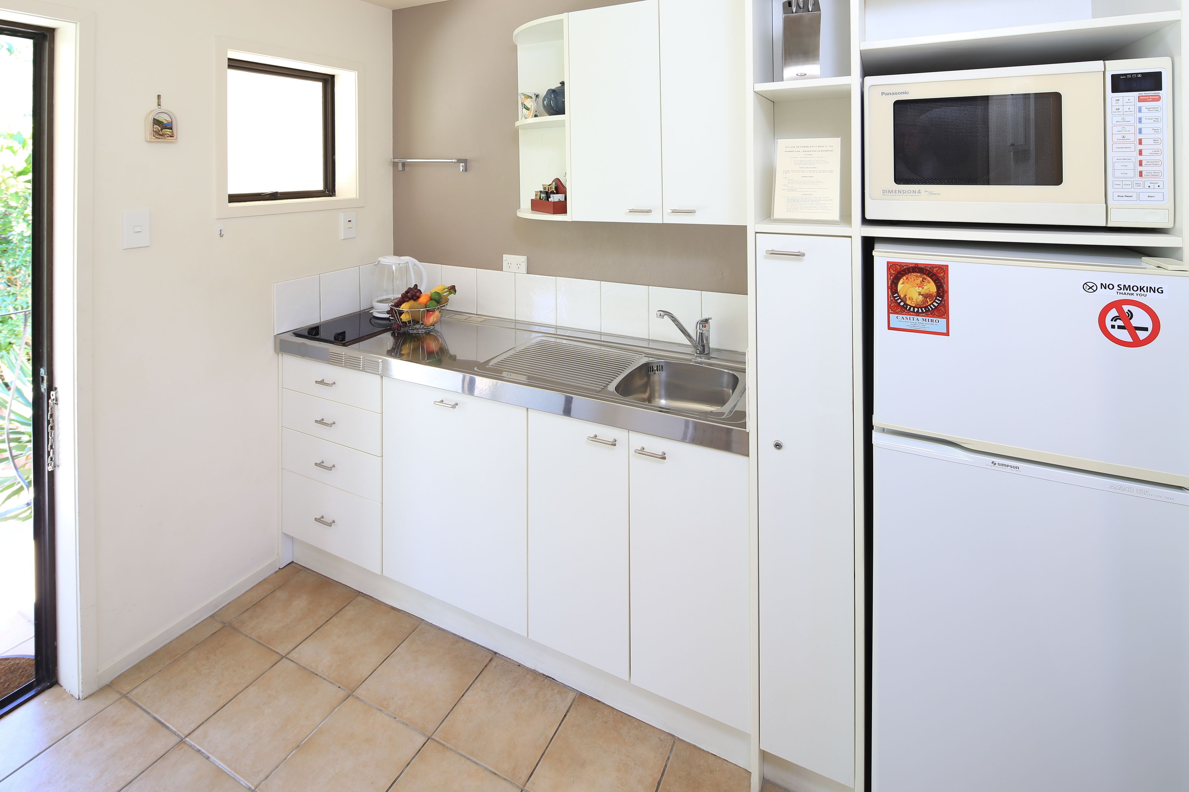 A modern kitchen with white cabinets, a sink, a microwave, and a refrigerator.