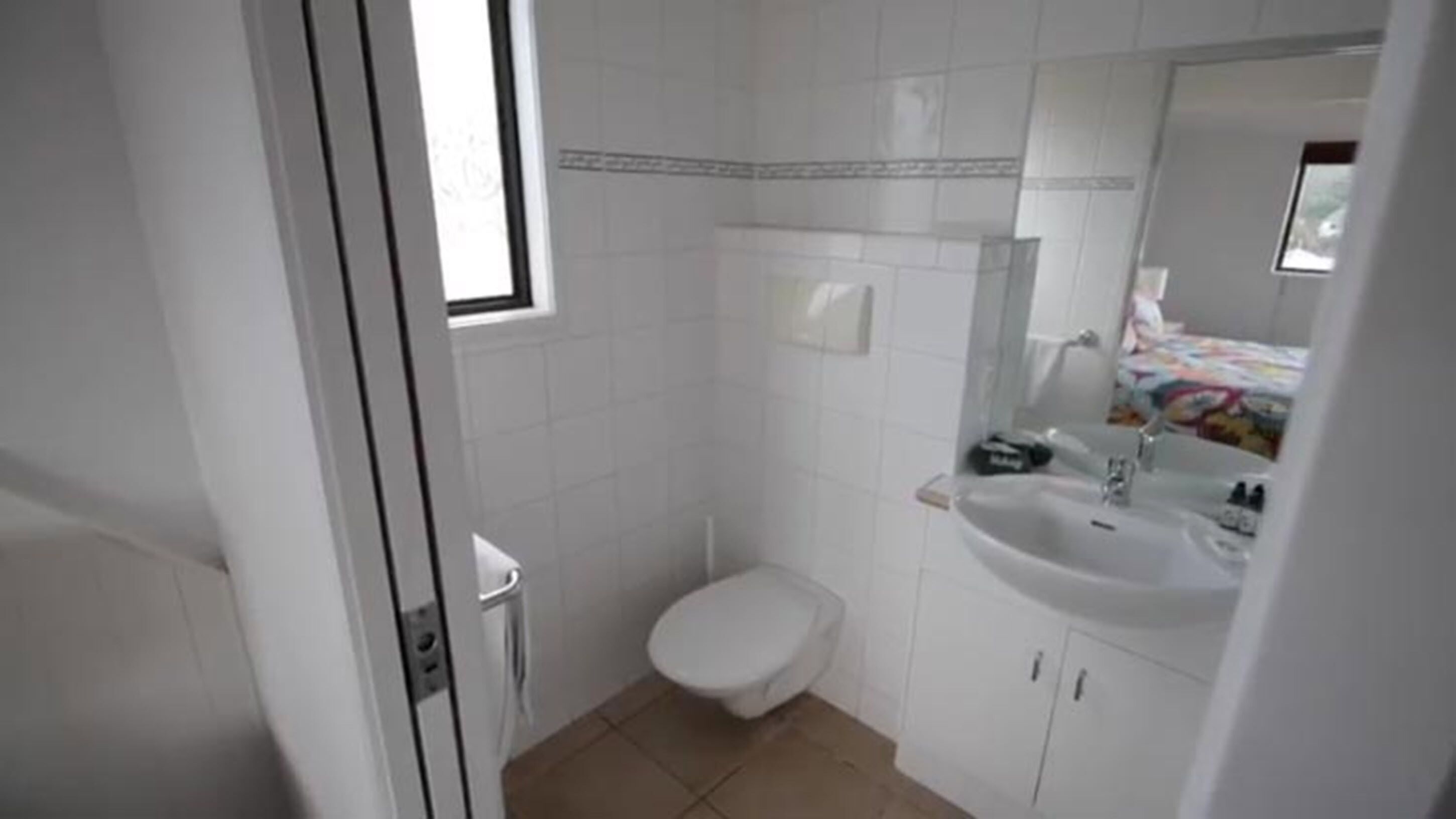 A small, white bathroom with a toilet, a sink, and a mirror.