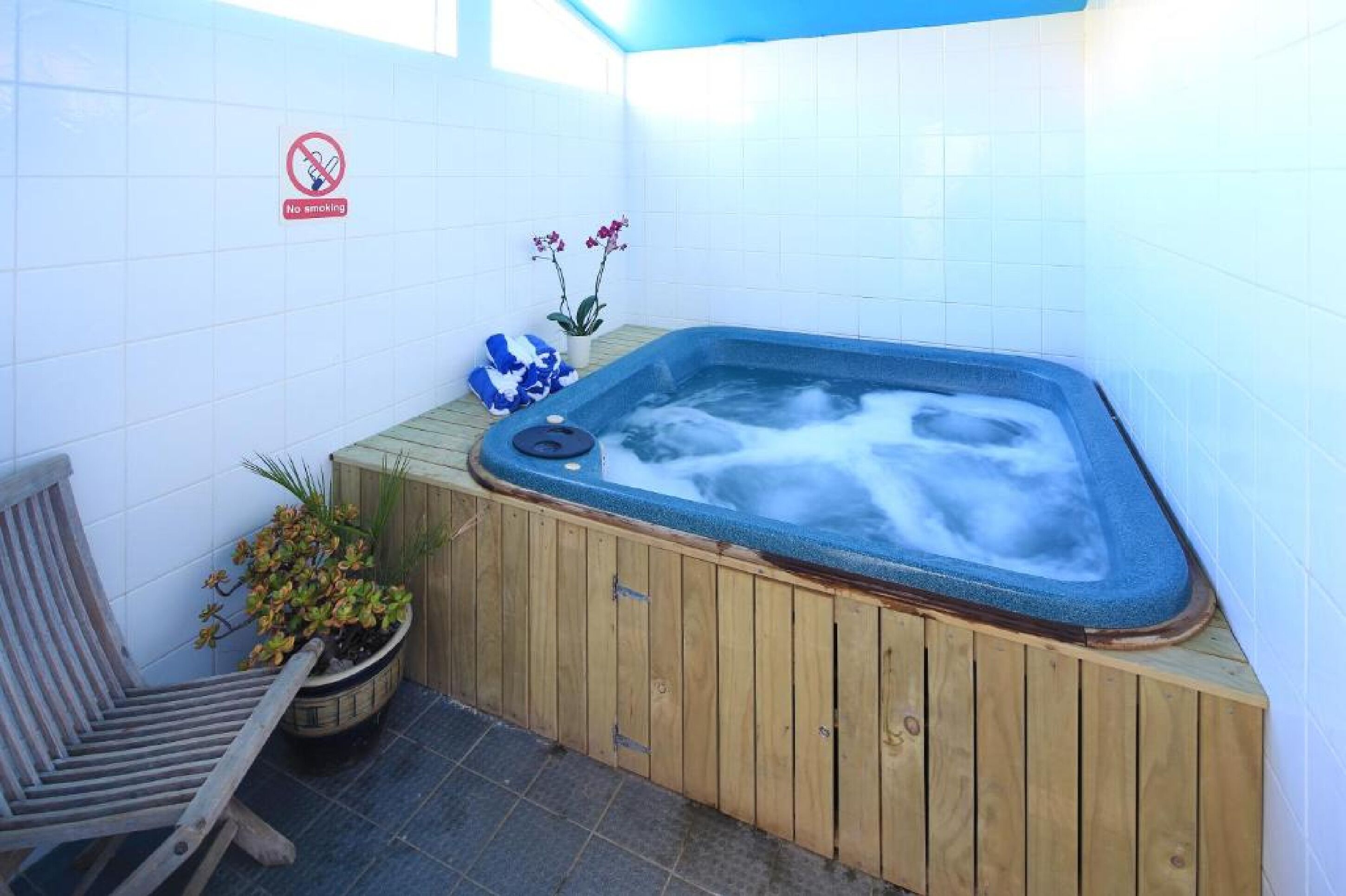 A hot tub with a wooden bench and a no-smoking sign.