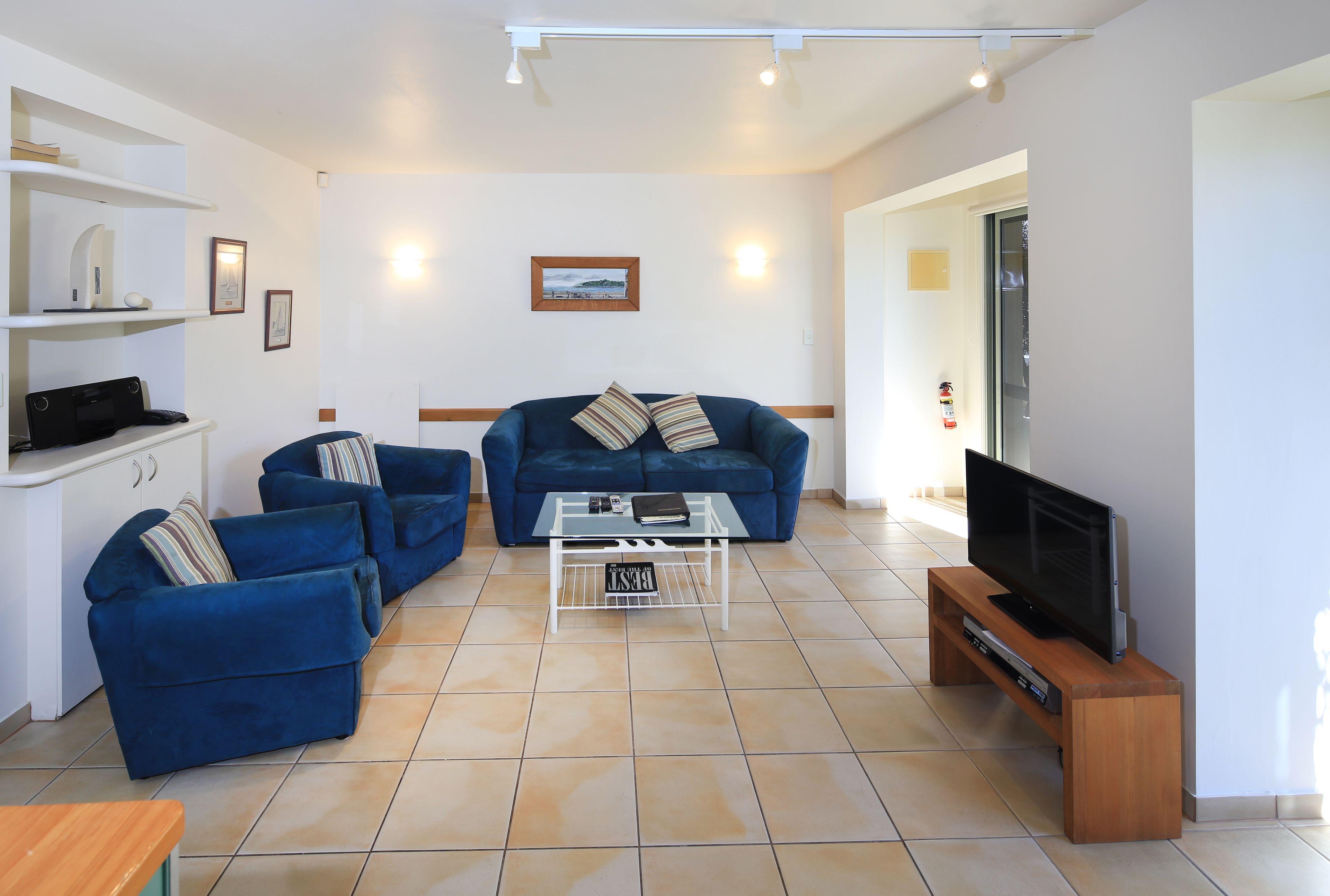 A living room with a sofa set, a coffee table, a TV on a wooden stand, and a fireplace.