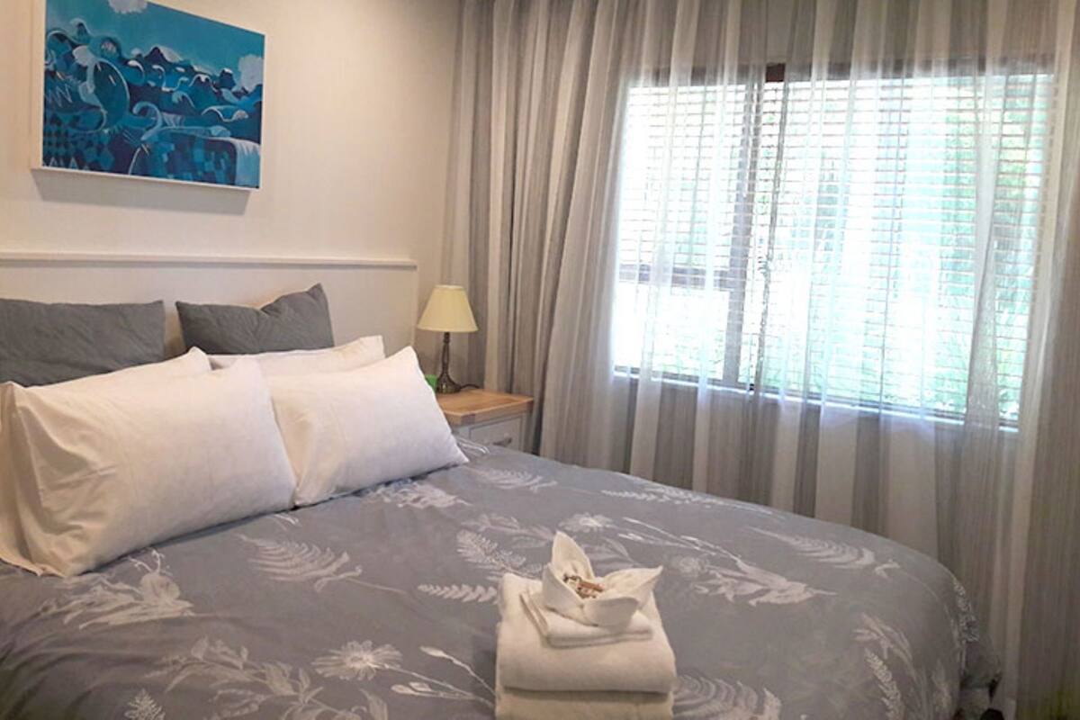 A neatly made bed with pillows, a bedside lamp, and a painting on the wall.