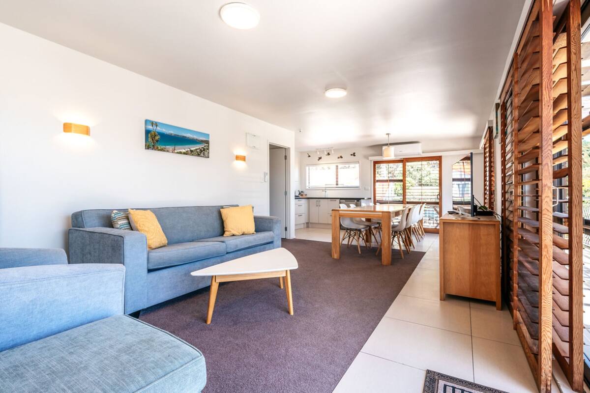 A modern living room with a sofa, a coffee table, and a dining area with a wooden table and chairs.