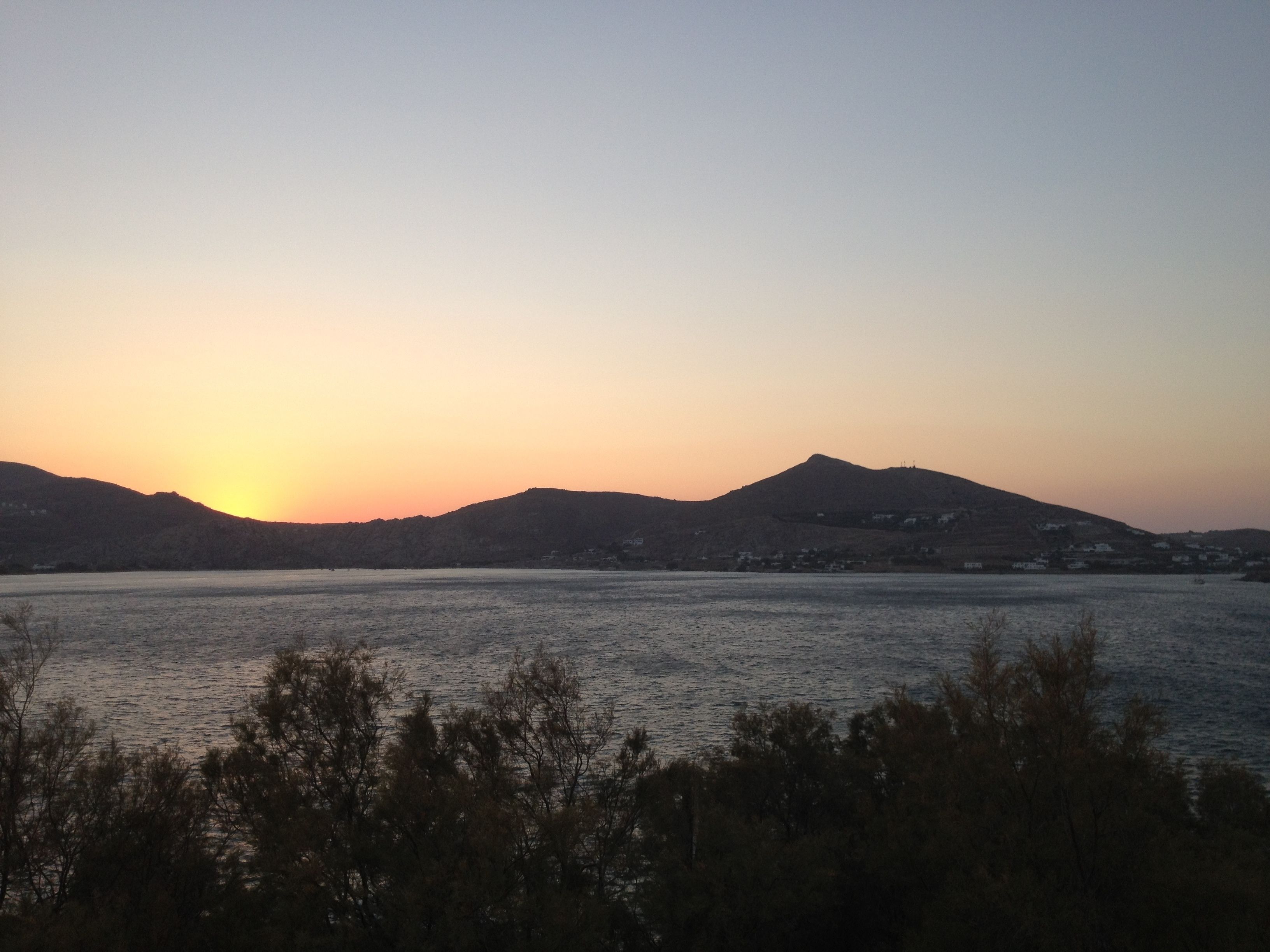 A sunset over a body of water with hills in the background.