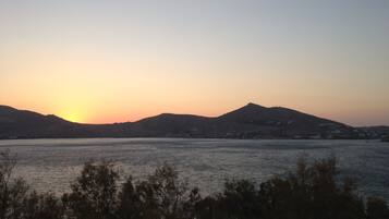 A sunset over a body of water with hills in the background.