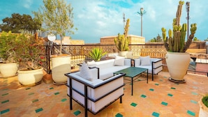 Eine Dachterrasse mit Sitzgelegenheiten im Freien, Topfpflanzen und freiem Blick zum Himmel.