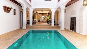 Ein Poolbereich mit einem klaren, blauen Pool, weißen Wänden und Bögen.