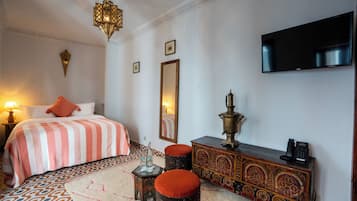 Une chambre d’hôtel avec un lit, une télévision, une commode et une lampe.