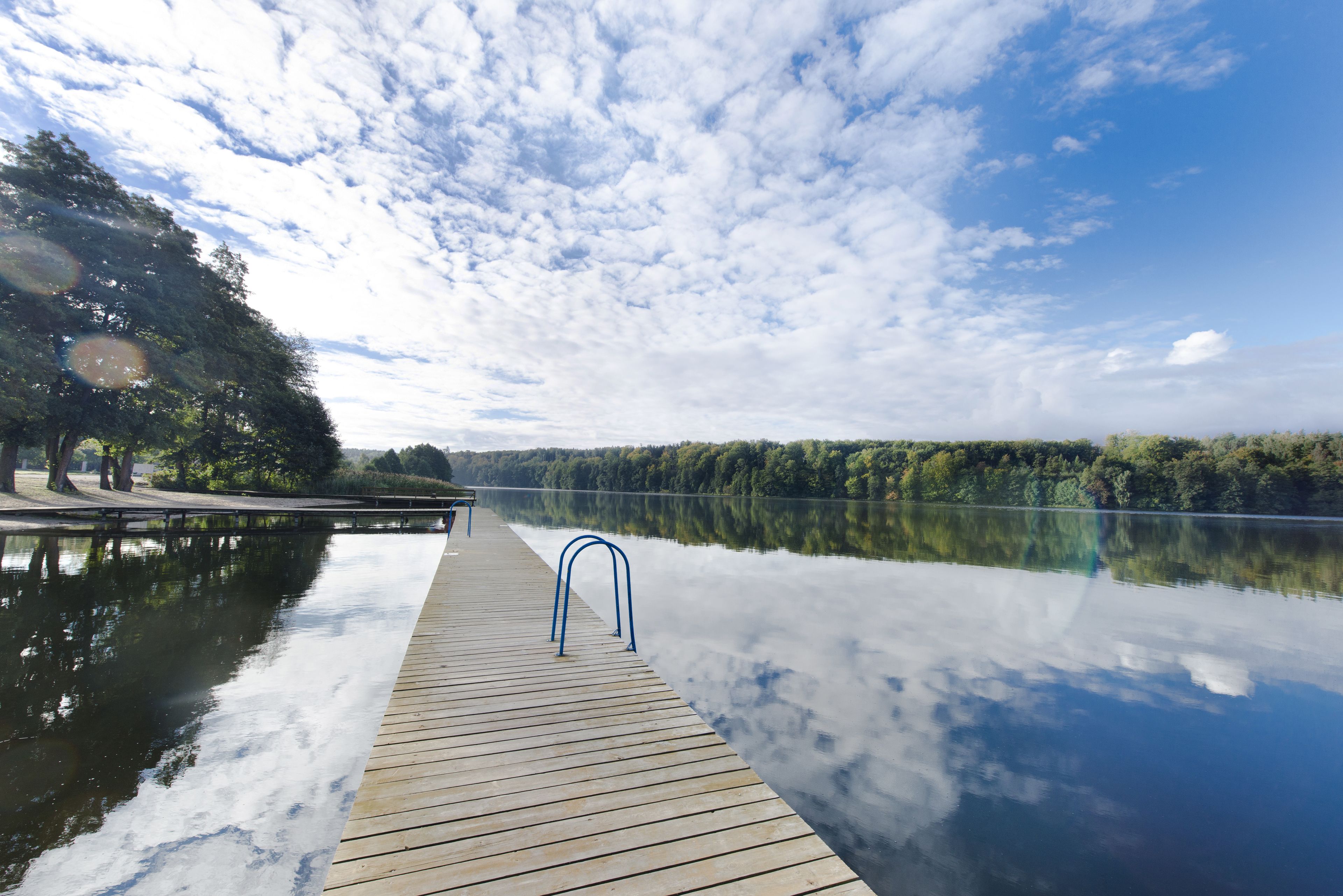 A wooden dock extending into calm water with a clear sky above.