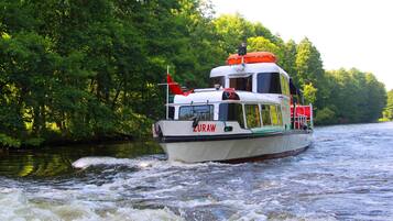 A boat named ZURAW on a river surrounded by dense green foliage.