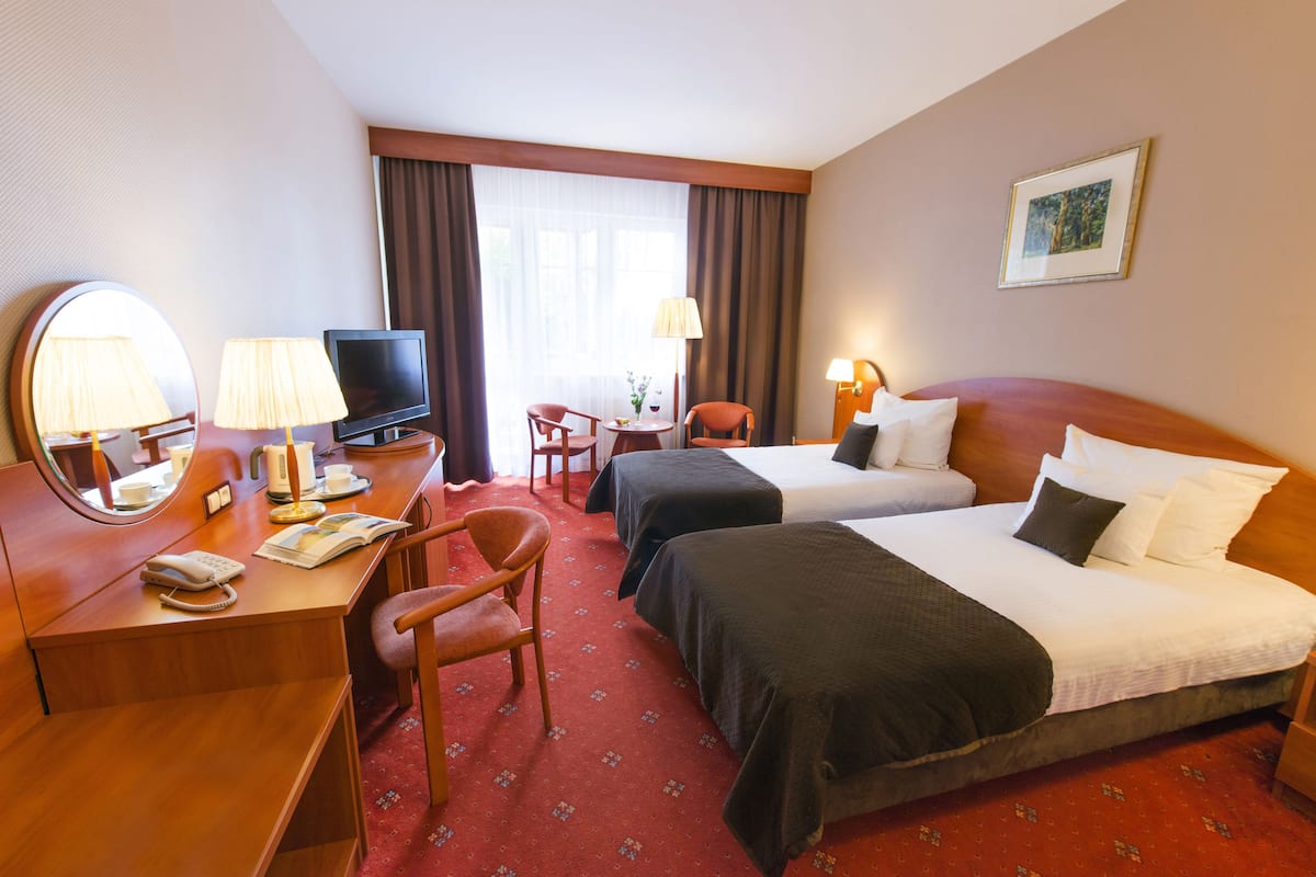 A hotel room with two beds, a desk with a telephone, a television, and a chair.