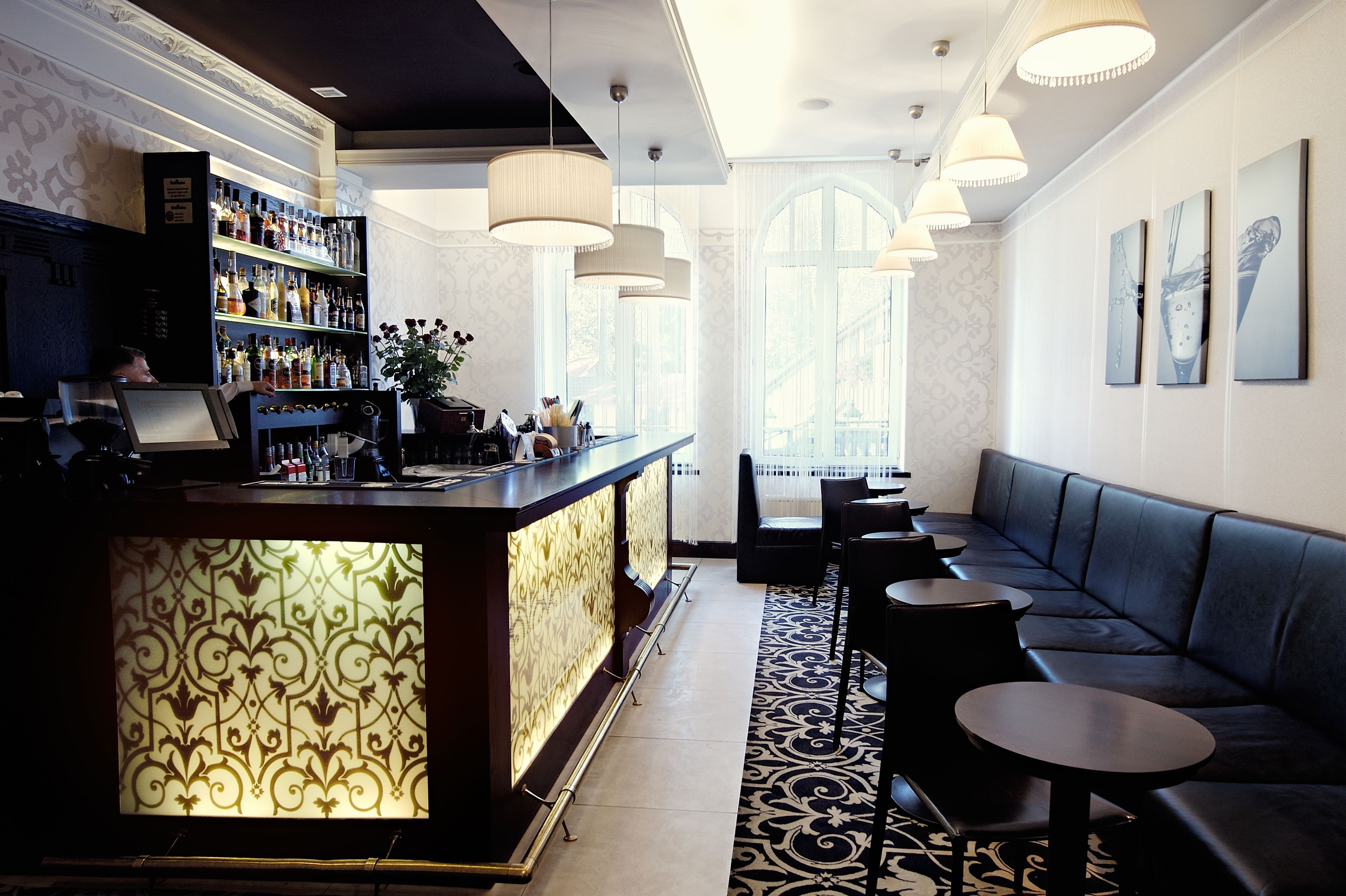 A bar area with a counter, shelves of bottles, and seating.
