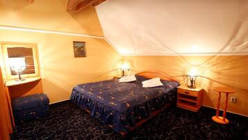 A bedroom with a bed, bedside tables, a bench, and a lamp.