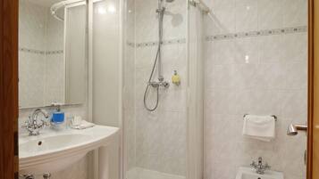 Un baño moderno con ducha de vidrio, lavamanos y bidé.