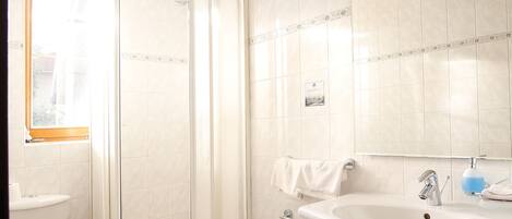 A modern bathroom with a shower, toilet, bidet, and sink.