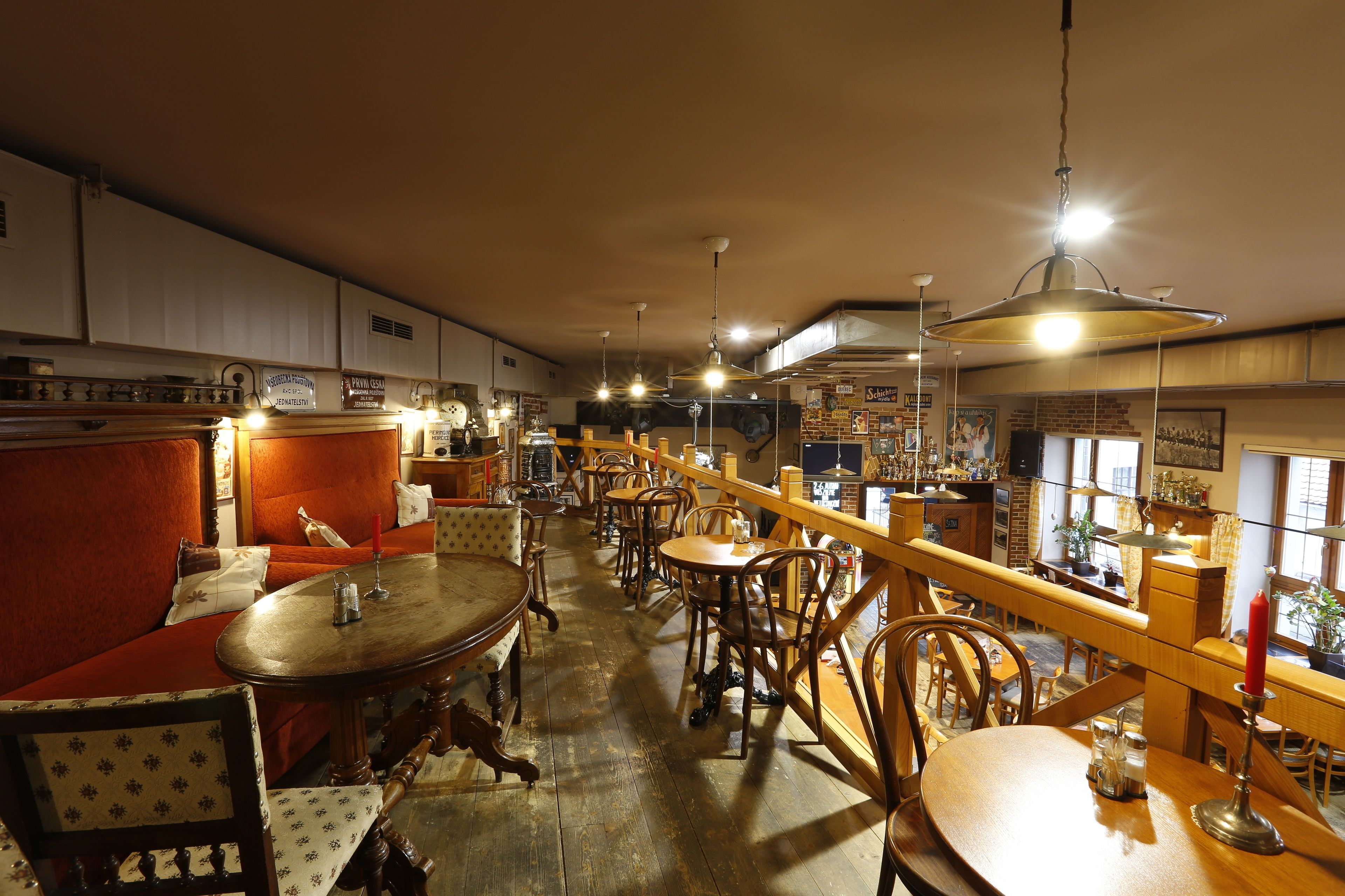A cozy restaurant with wooden furniture, a bar area, and a view of the street through large windows.