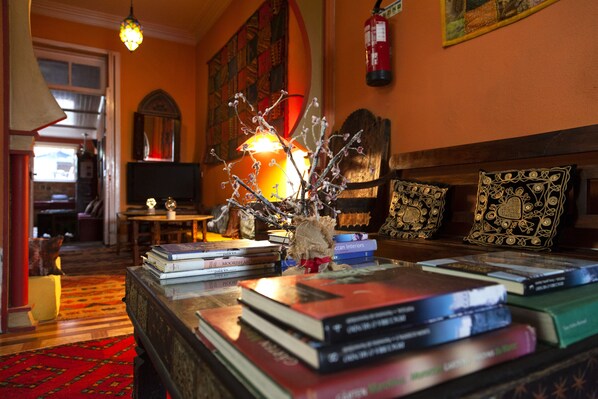 A cozy reading area with a fireplace, books, and a decorative vase.