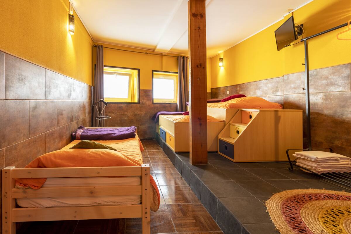 A room with two wooden beds, a massage chair, and a small seating area.