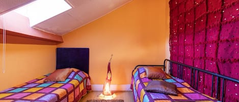 A bedroom with two beds, a skylight, a red curtain, and a decorative floor lamp.