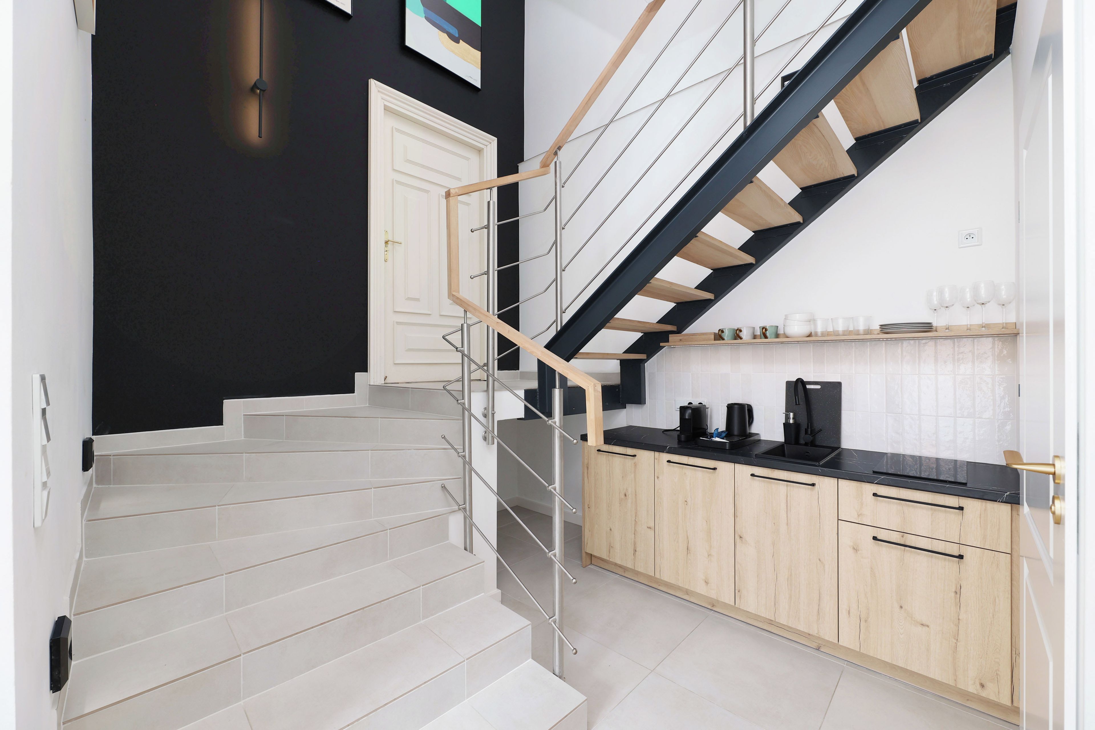 Une cuisine moderne avec un escalier en bois et un mur noir.