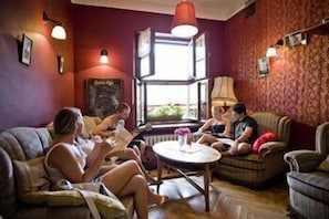 Un rincón salón acogedor con asientos, una mesa, un ventanal con vistas y lámparas fijadas a la pared.
