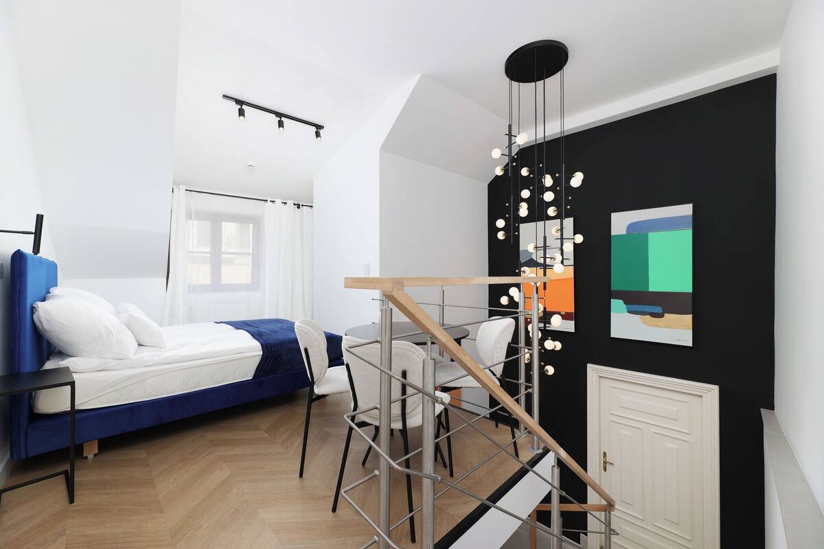 A modern room with a bed, a desk, and a staircase.