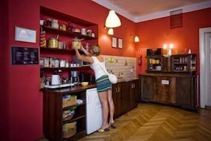 Una cocina con armarios de madera, un refrigerador y una persona alcanzando objetos en los estantes.