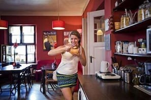 Una cocina con pared roja, ventana y mostrador con varios objetos.